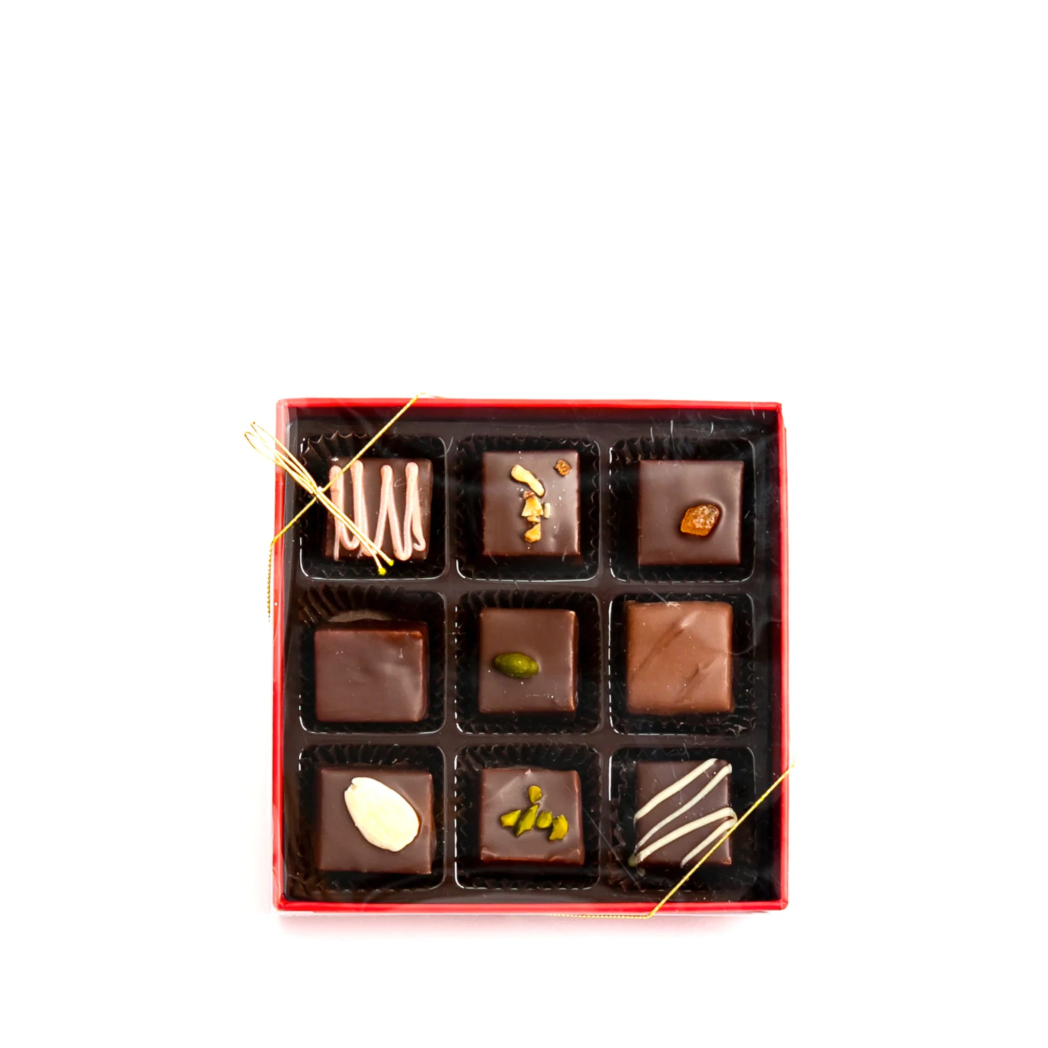 A Lebkuchen box of chocolates with a clear lid, filled with 9 different gingerbread chocolates with a gold bow.