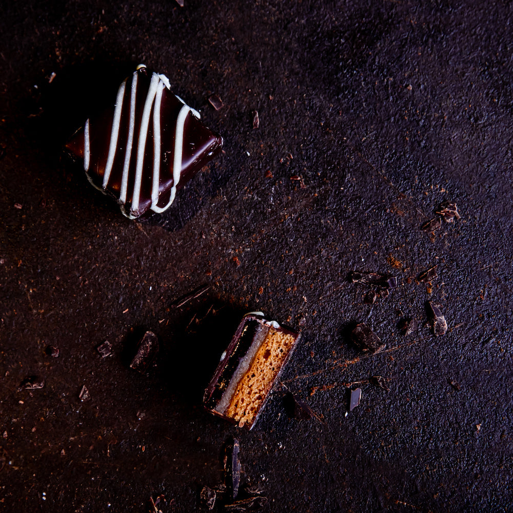 Handgefertigte Lebkuchen Pralinen gefüllt mit Marzipan und Ribisel-Gelee umhüllt von dunkler Schokoladekuvertüre und verziert mit Weißer Schokoladekuvertüre.